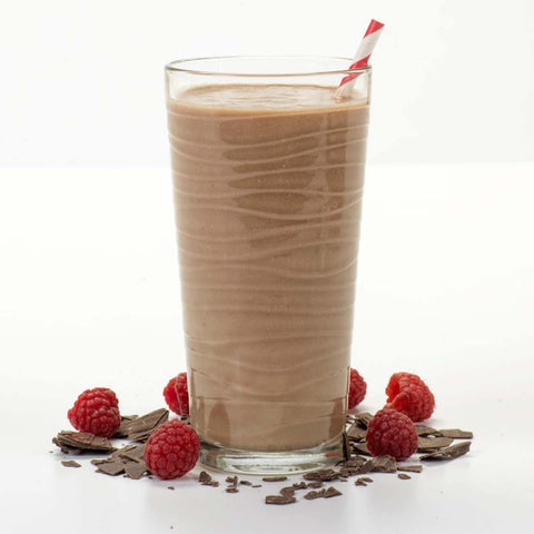  A glass of chocolate milk topped with fresh raspberries.