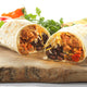 A delicious burrito with a filling of meat, beans, cheese, and vegetables, wrapped in a soft tortilla.