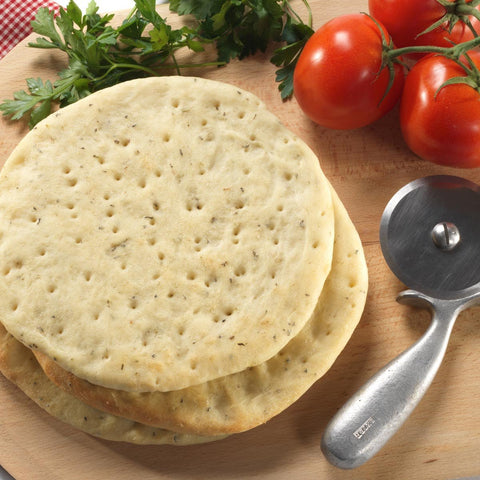 A cutting board with three flatbreads and a tomato, perfect for a delicious Mediterranean meal.