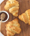 Croissants drizzled with honey and chocolate sauce on a white plate.